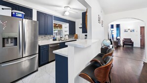 Een moderne keuken met roestvrijstalen apparatuur, een centraal eiland en blauwe kastjes.