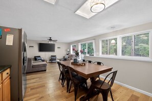 A modern kitchen with a dining area, a flat-screen TV, and a ceiling fan. - Torch + Timber House (Rapid City)