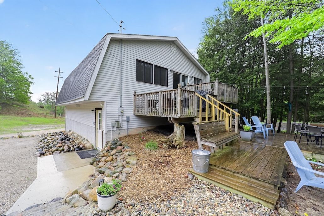 A single-story house with a deck, outdoor seating, and a small garden area.
