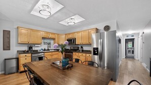Uma cozinha moderna com armários de madeira, eletrodomésticos de aço inoxidável e uma área de jantar com mesa de madeira.