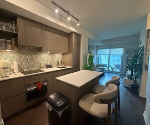 A modern kitchen with a central island, built-in appliances, and a view to a living area.