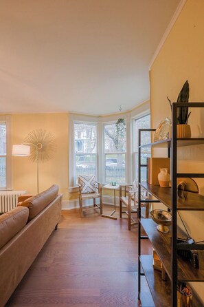A cozy living room with a brown leather sofa, wooden chairs, a small table, and a bookshelf. - Historic 2-Bed Charm in the Heart of Central Moscow (Moscow)