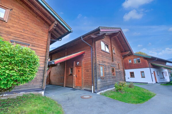 A wooden building with a red awning, a door, and windows. - Feriendorf Wildschonau-near ski Area (Wildschönau)