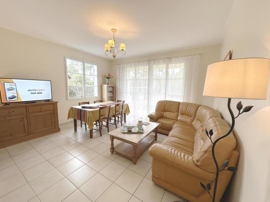 A living room with a sofa, a coffee table, a TV, and a chandelier.