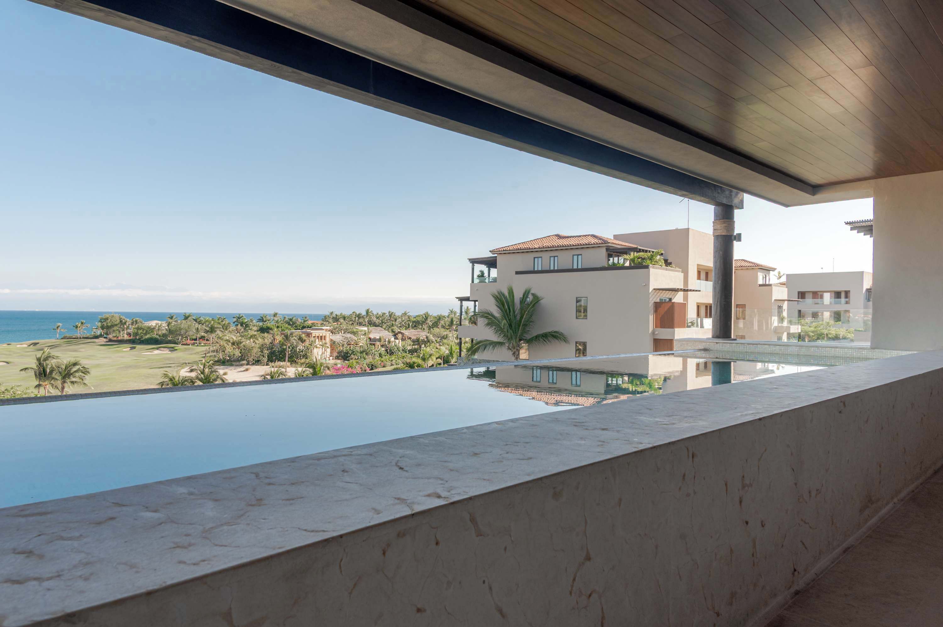 Un hotel moderno con una amplia piscina infinita con vistas a una playa y al océano.