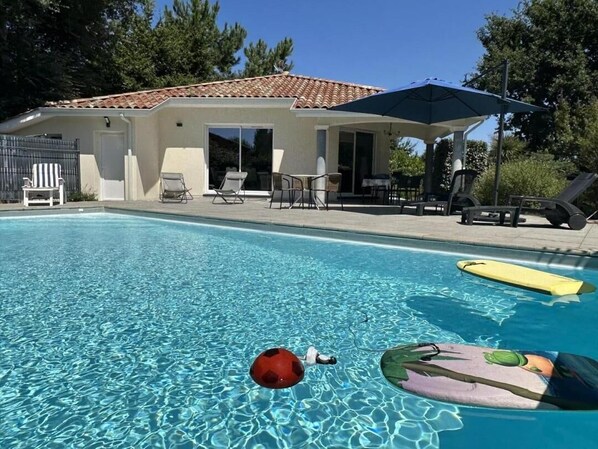 A swimming pool with lounge chairs and umbrellas, surrounded by a house with a tiled roof. - Le Ferrognard - LINXE (LINXE)