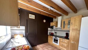 Een keuken met houten kastjes, een spoelbak, een fornuis en een magnetron.