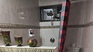 Et badeværelse med flisegulv, toilet, håndvask og dekorative glasvaser.