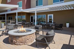 An outdoor patio with a fire pit, seating, and a covered area with tables and chairs.