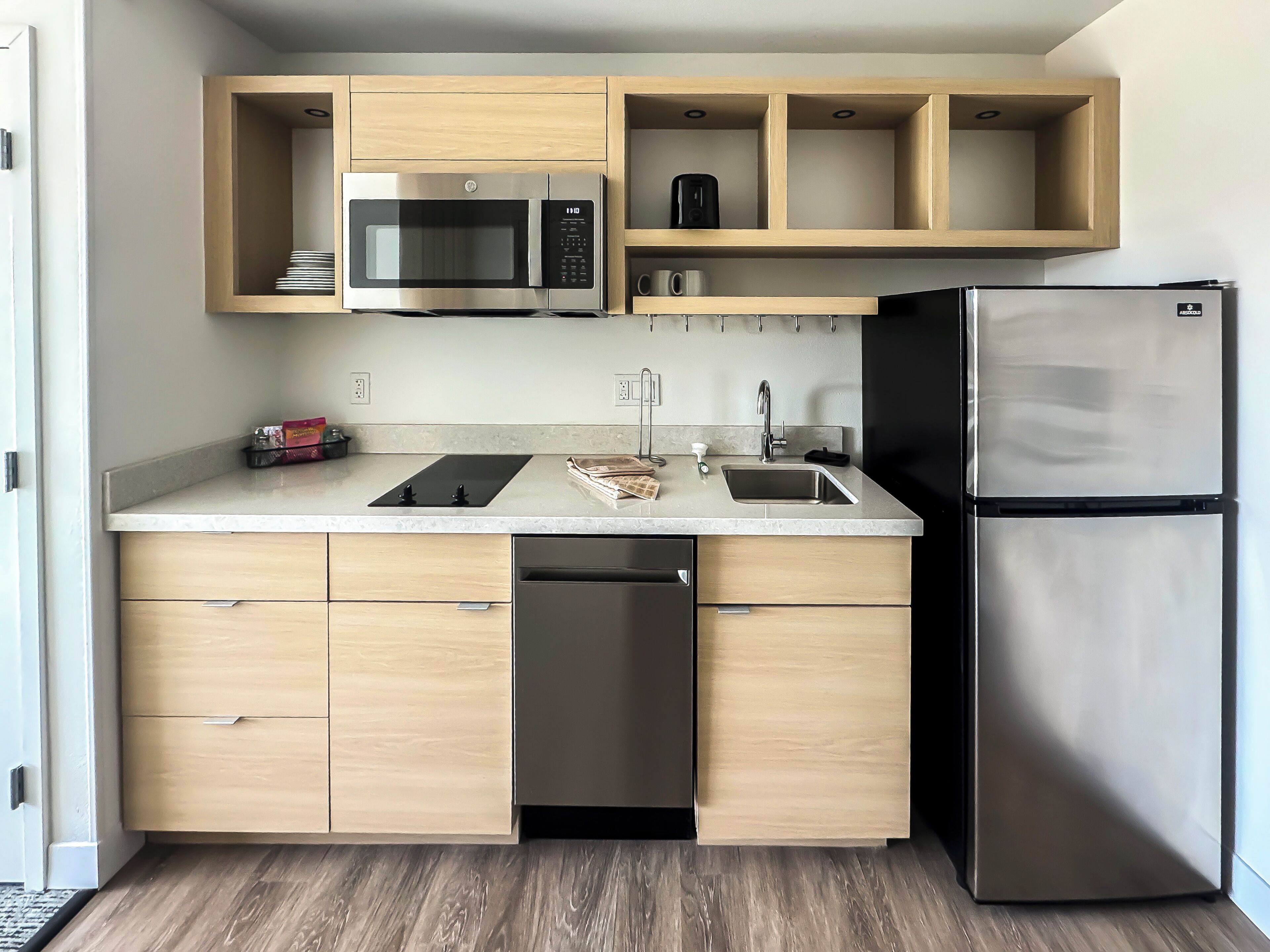 A modern kitchen with a built-in microwave, coffee maker, and refrigerator.