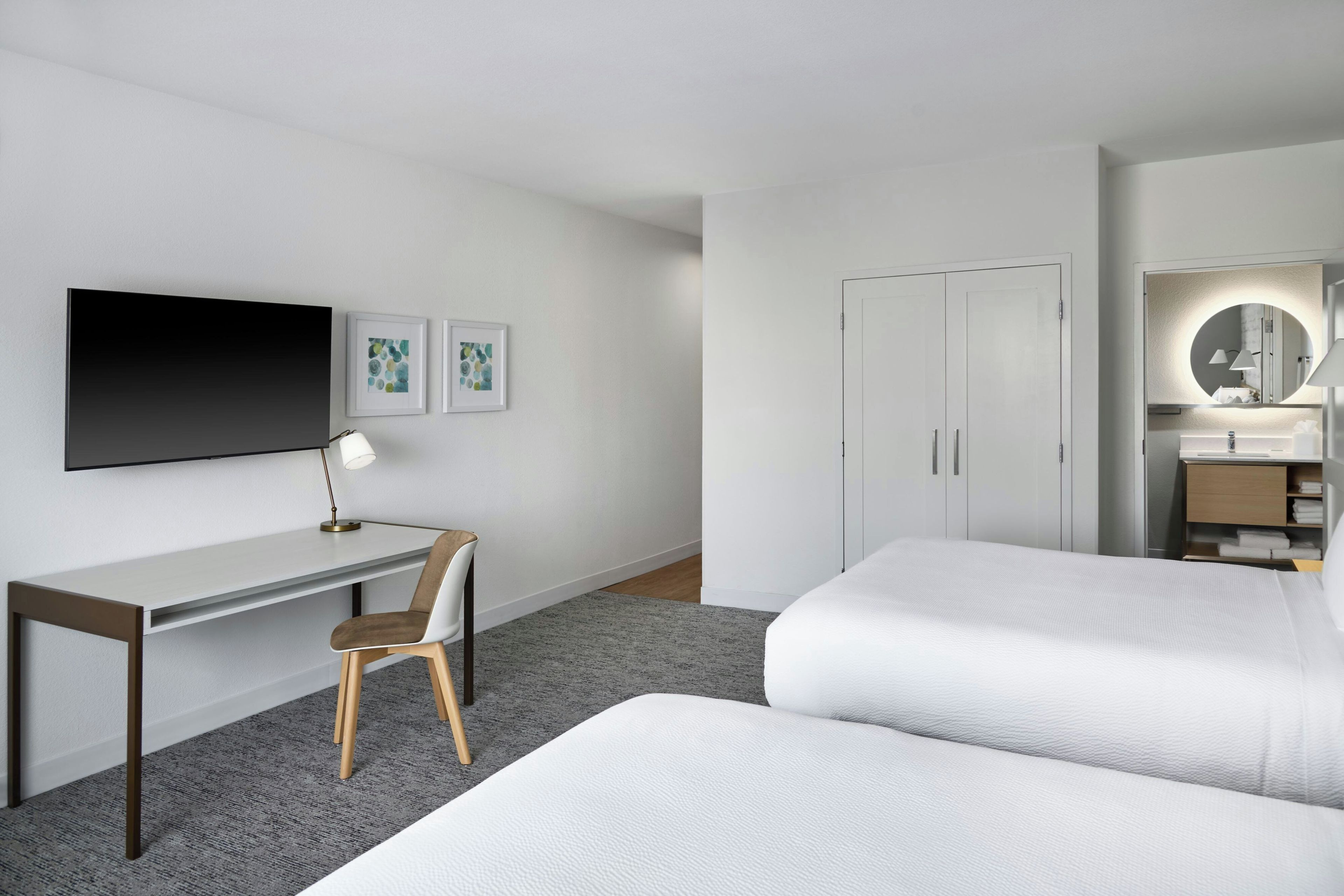 A hotel room with a bed, a desk, a chair, a television, and a wardrobe.