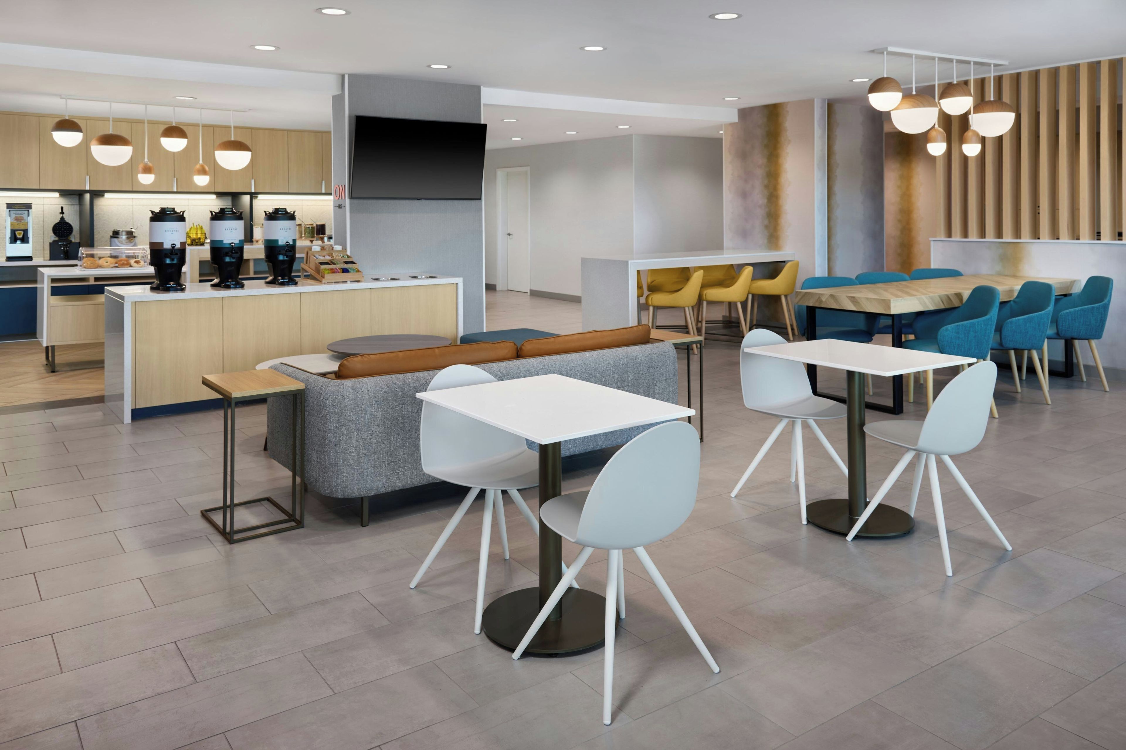 A modern dining area with a central island, seating arrangements, and a kitchen area with appliances.