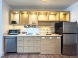 A compact kitchen with built-in appliances, wooden cabinets, and a stainless steel refrigerator.