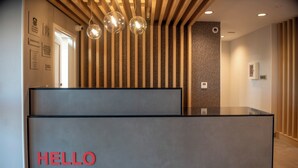 Un comptoir d’accueil avec une enseigne indiquant « BONJOUR, Ridgecrest », des lambris en bois sur le mur et un luminaire moderne.