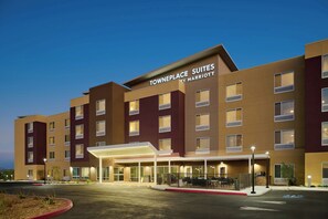A hotel with a modern design, featuring a prominent entrance with a covered walkway and a sign that reads 'TOWNPLACE SUITES BY MARRIOTT'.