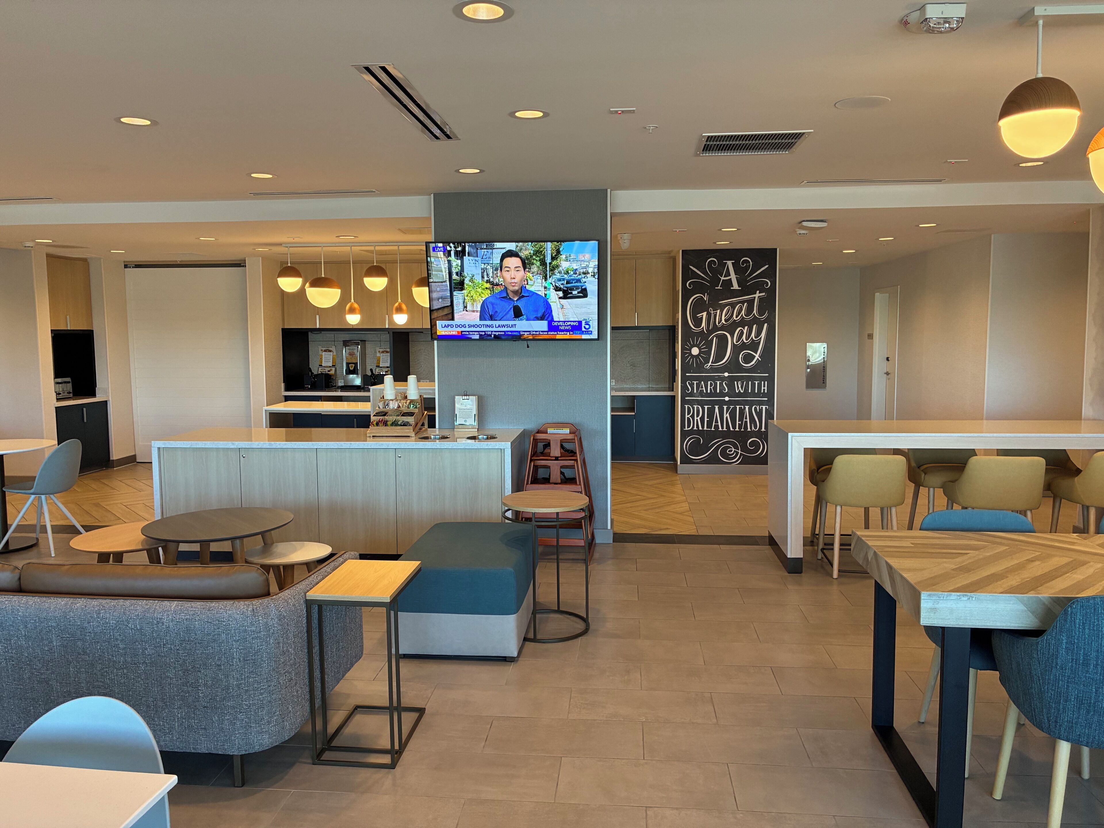 Un moderno vestíbulo de hotel con una zona de bar, asientos y un televisor mostrando un noticiero.