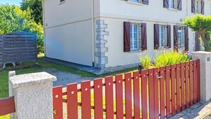 Ein zweistöckiges Haus mit rotem Zaun im Vordergrund.
