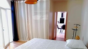 A bedroom with a large bed, a chair, and a desk.