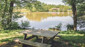 A wooden picnic table by a calm lake surrounded by trees.