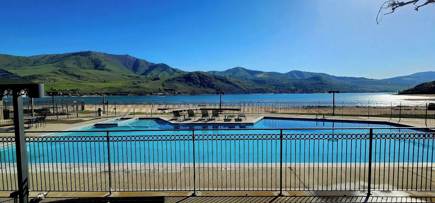 A swimming pool with a view of mountains and a lake.