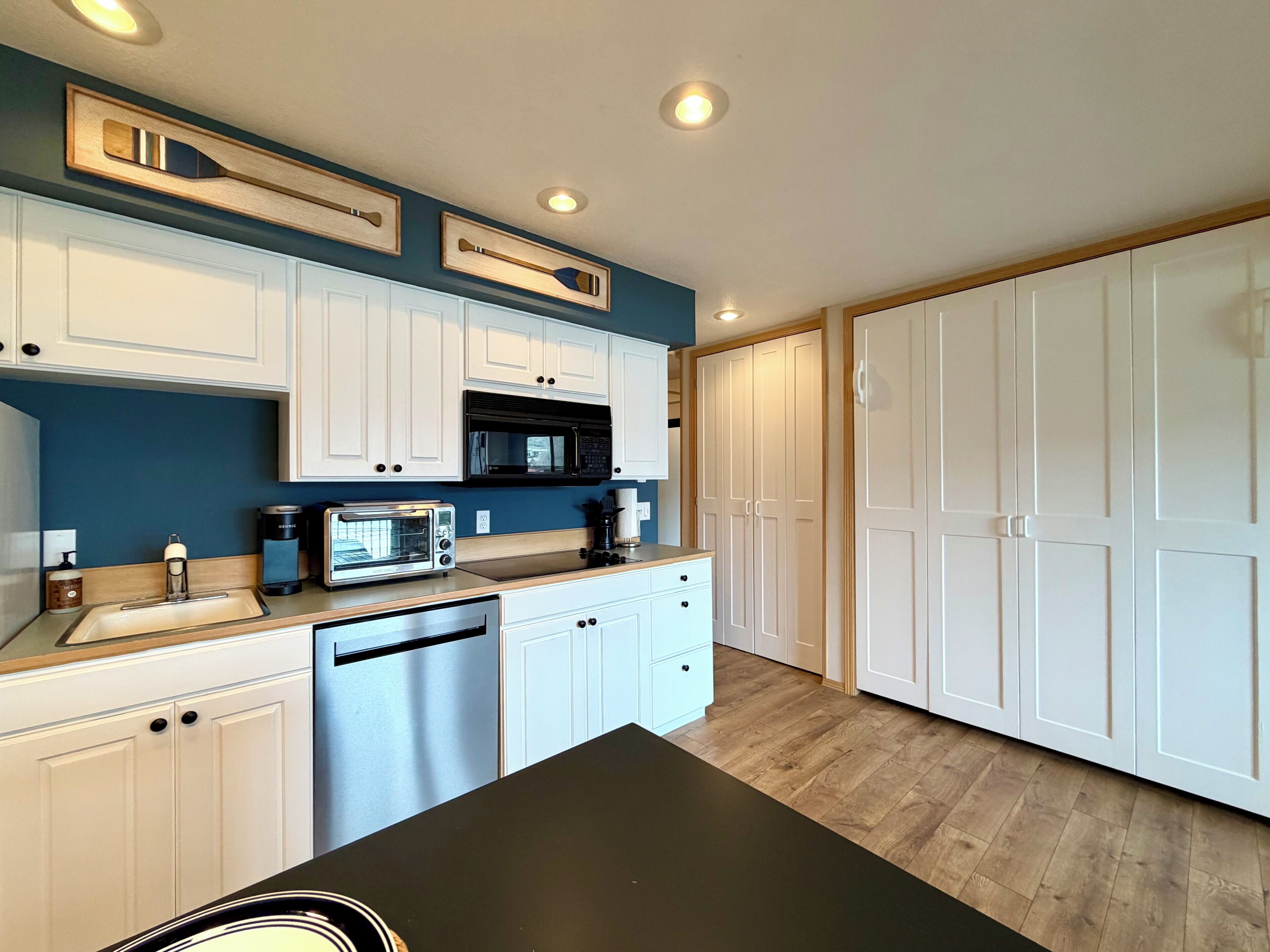 A modern kitchen with white cabinets, a microwave, a toaster, and a coffee maker.