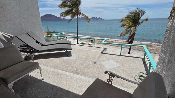 Een balkon met lounge stoelen met uitzicht op een strand en de oceaan.
