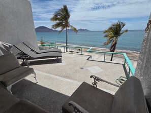 A balcony with lounge chairs overlooking a beach and the ocean. - Ocean-View Condo at Playa San Francisco  Prime Beachfront Location (San Carlos)