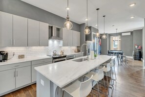A modern kitchen with a central island, bar stools, and pendant lighting. - 12 Min to Broadway - Sleeps 10 - Rooftop + Parking (Nashville)