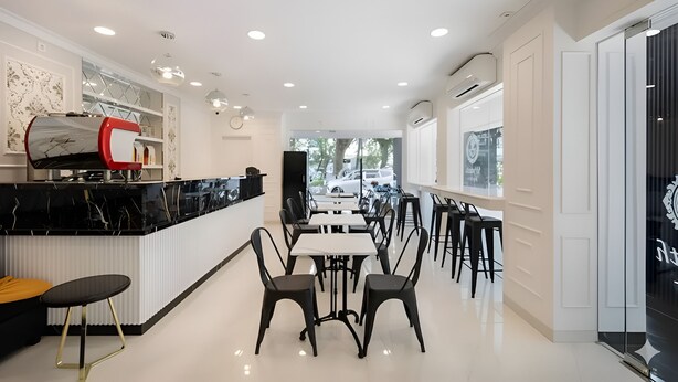 A modern restaurant with a black marble counter, white walls, and a long dining area with black chairs. - Wyneth Hotel Airport (Tangerang)