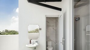 A modern bathroom with a pedestal sink, a mirror, and a toilet. - Wyneth Hotel Airport (Tangerang)