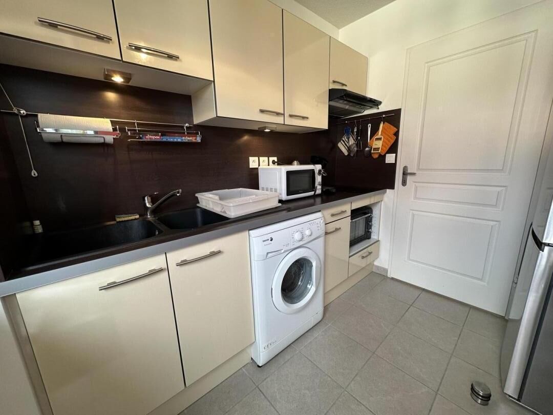 A compact kitchen with a washing machine, microwave, and oven.
