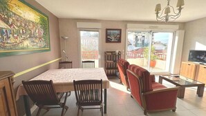 Amplia sala de estar con una mesa de comedor, sillas, un sofá y un televisor.