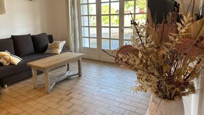 Un soggiorno con un divano scuro, un tavolino in legno e un'ampia finestra vista su spazi verdi.