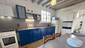 Cucina con mobili blu, piano cottura bianco e tavolo da pranzo con sedie.