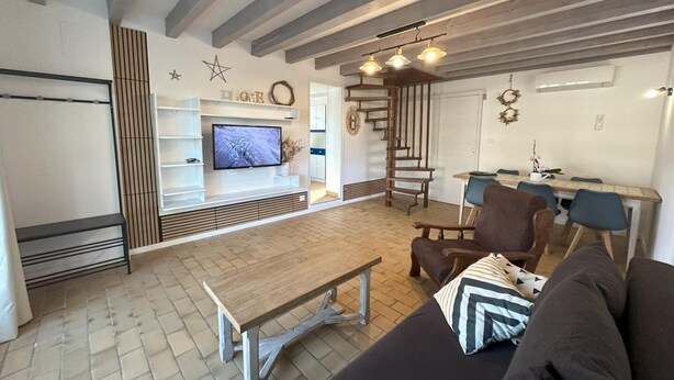 Un soggiorno moderno con un tavolino in legno, un divano e una TV montata su una parete bianca.