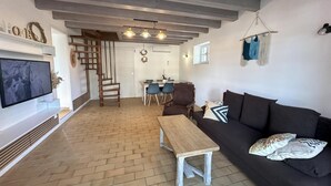 Un soggiorno con televisore, mobili in legno, un divano e una scala che conduce a un'altra stanza.