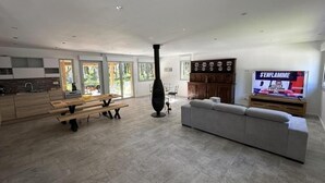 A modern living room with a fireplace, a sofa, a TV, and a dining area with a bench. - La résinière - MAGESCQ - Gîte (MAGESCQ)