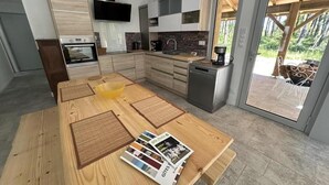 A modern kitchen with wooden cabinets, a built-in oven, and a coffee maker. - La résinière - MAGESCQ - Gîte (MAGESCQ)