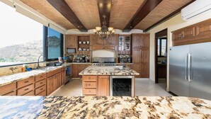 A kitchen with granite countertops, wooden cabinets, a stainless steel refrigerator, and a built-in oven. - Spacious 3 Bedrooms with Private Pool in Cabo’s Pedregal (Cabo San Lucas)