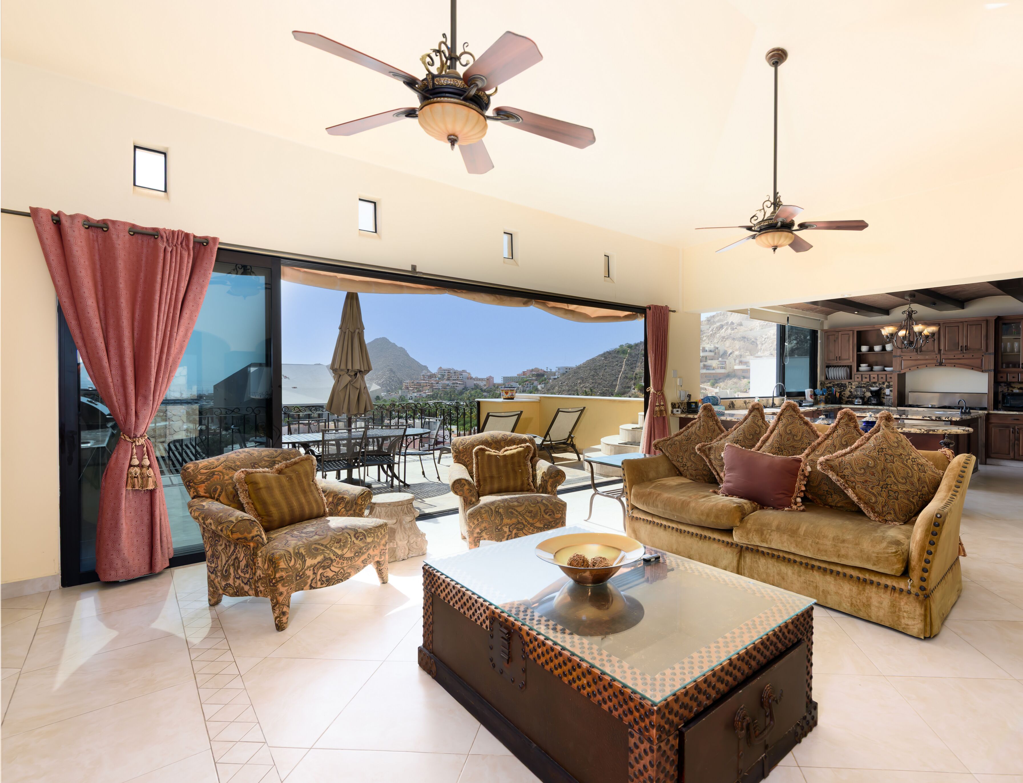 A spacious living area with a large window offering a mountain view, furnished with a sofa, chairs, and a coffee table.