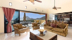 A spacious living area with a large window offering a mountain view, furnished with a sofa, chairs, and a coffee table. - Spacious 3 Bedrooms with Private Pool in Cabo’s Pedregal (Cabo San Lucas)