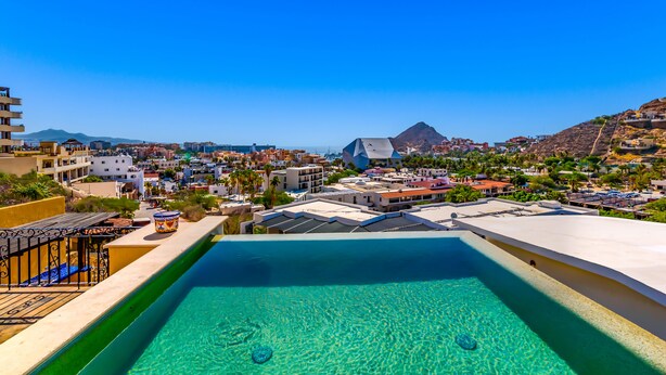 A rooftop pool with clear blue water, surrounded by buildings and a mountain in the background. - Spacious 3 Bedrooms with Private Pool in Cabo’s Pedregal (Cabo San Lucas)