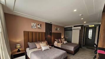 A hotel room with two beds, a nightstand, a lamp, and artwork on the walls.