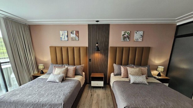 A hotel room with two beds, a central divider, and artwork on the walls.