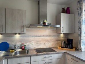 Una cocina moderna con un lavaplatos de acero inoxidable, un horno empotrado y una cafetera en la encimera.