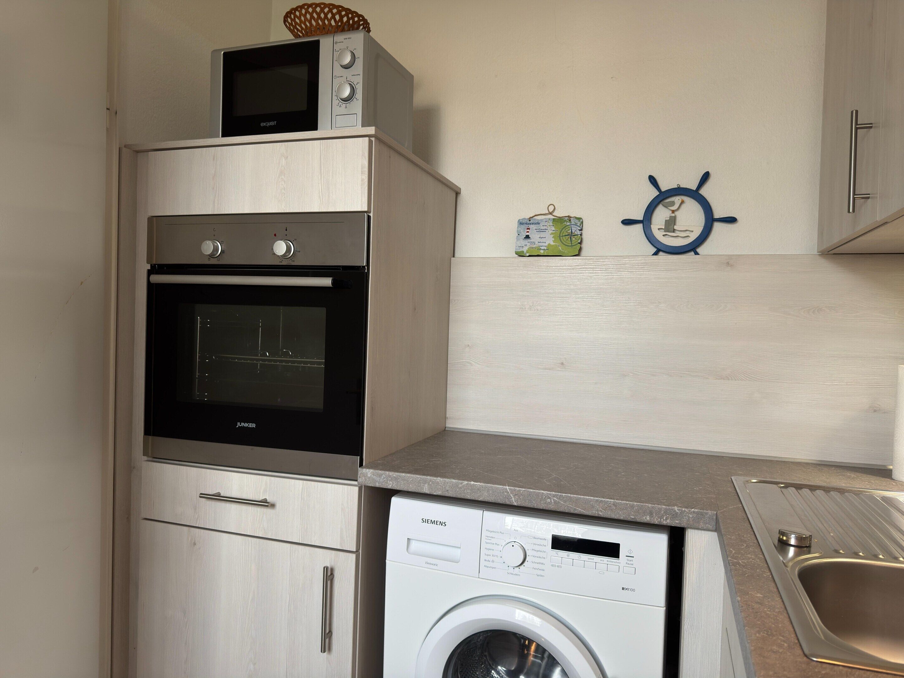 A compact kitchen with a built-in oven, microwave, and washing machine.