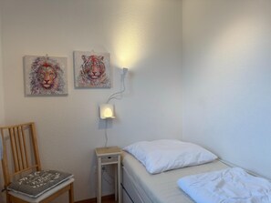 Makuuhuoneessa on sänky, tuoli ja kaksi seinälle ripustettua taulua.