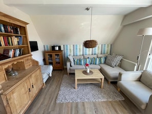 A living room with a sofa, a coffee table, a bookshelf, and a cabinet. - Ferienhaus in Dornumersiel (Dornum)