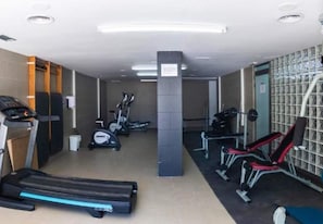 Una palestra con tapis roulant, macchinari ellittici e panche per pesi.