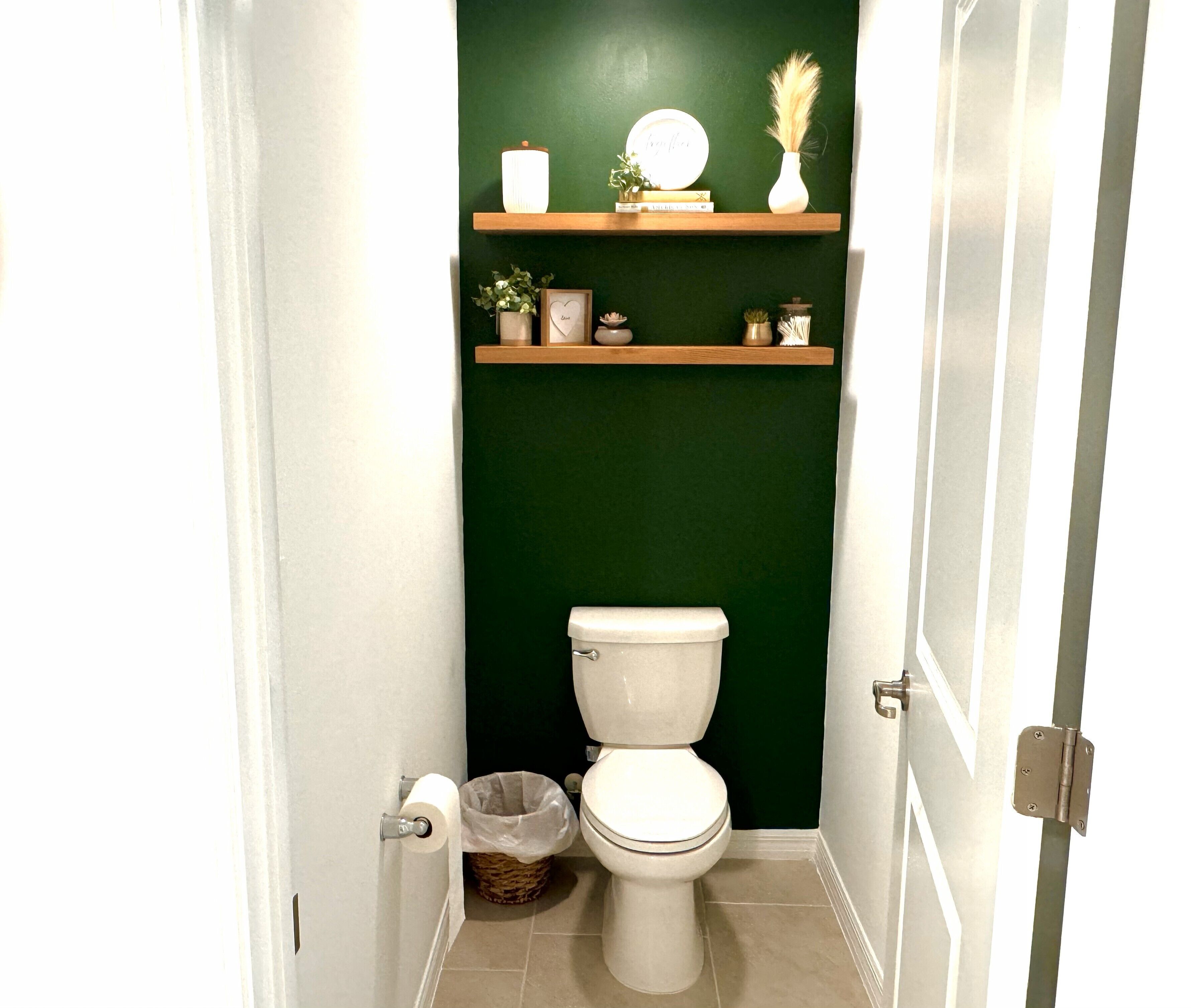 Une petite salle de bain avec des toilettes, une poubelle et deux étagères au-dessus des toilettes.